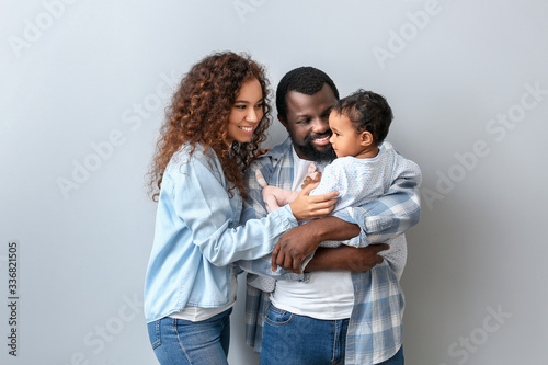 Happy African-American parents with cute baby on white background