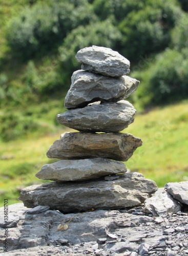 A rock cairn created on a hiking trail in Switzerland rests peacefully on a boulder.