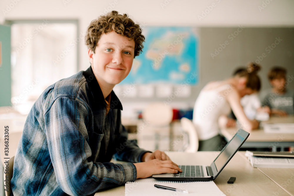 Portrait of teenage boy using laptop while sitting in classroom Portrait of teenage boy using laptop while sitting in classroom
