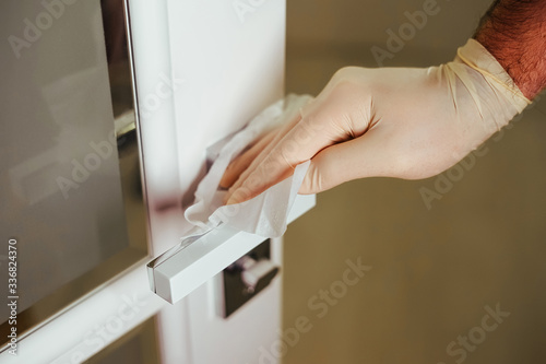 A gloved hand washes the surface of the door surface. Wet door handle processing. Disinfection against bacteria and viruses.