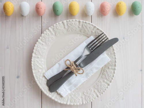 easter eggs, plate, vintage cutlery and napkin on wooden board. table set