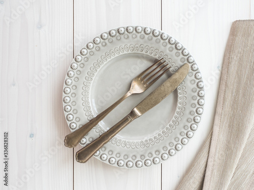 plate, vintage cutlery and placemat on wooden board. table set