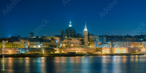 Malta's capital city Valletta, at night, from across the port in Sliema, with churches and buildings illuminated © Em Campos