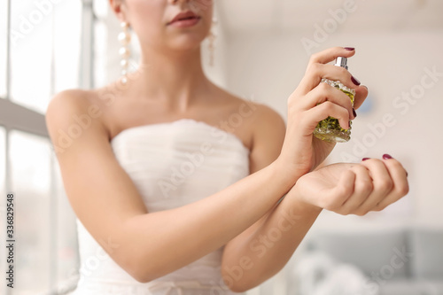 Beautiful young bride with perfume at home