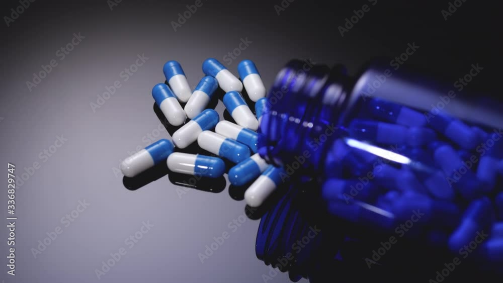 Pills and a jar slide on a mirror surface. Pharmaceuticals and Medicines