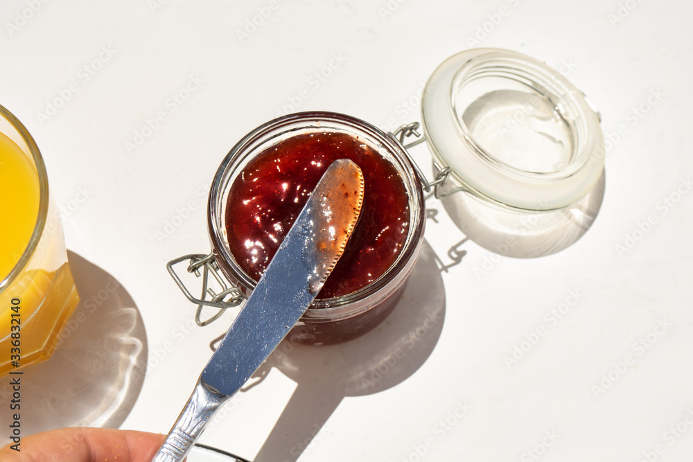 Strawberry jam in glass jar on white background