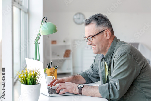 Mature man using laptop at ...