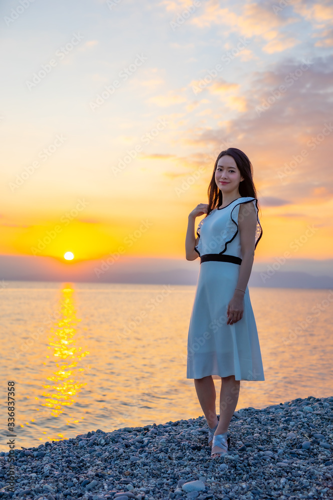 夕日の浜辺を歩く女性