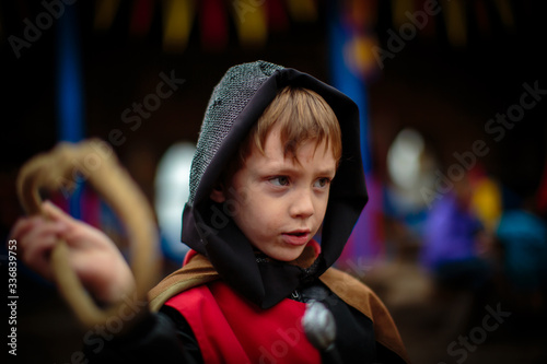 young kid playing with a costume of knight, in a medieval festival, resembling dark ages. 