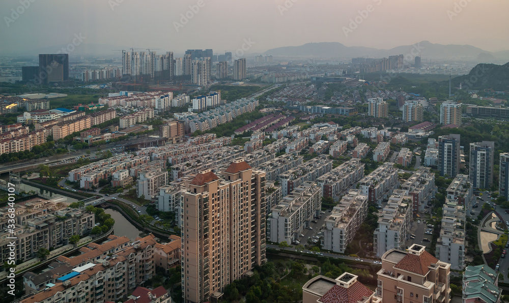 Suzhou China - May 2, 2010: Aerial evening shot over many rows of gray and brown residential highrise buildings. Streets, canals and green foliage in between.