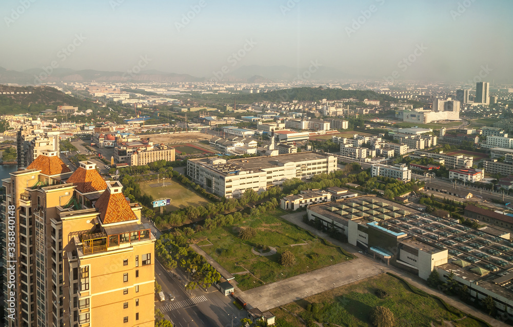 Suzhou China - May 3, 2010: Aerial morning shot over industrial and business district with plants and factories. Wider view over city with hazy mountains on horizon.