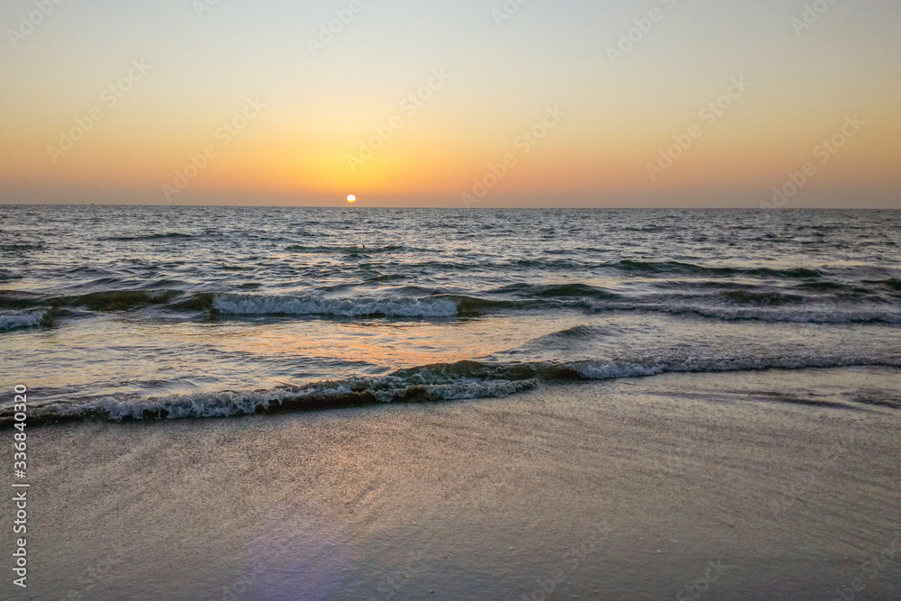 Cloudless Sunset over the sea, dark sea waves, sun glare and color lighting.