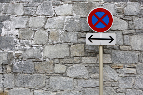 Panneau de signalisation routière le long d'un mur en pierre. Interdiction de stationner dans les deux sens.
