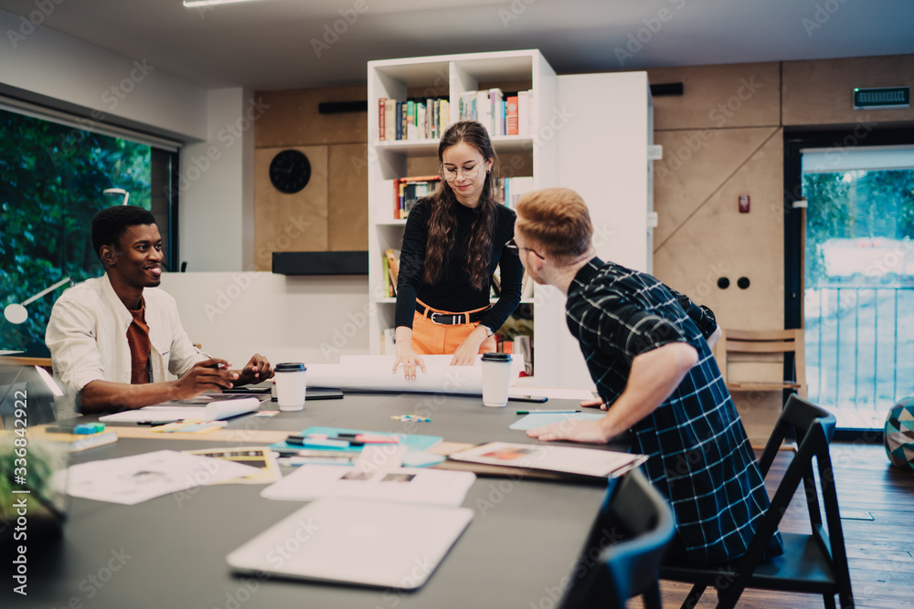 Progressive multiracial male and female architects developing startup design project during collaboration in modern coworking space, smart casual group of millennial brainstorming at desktop