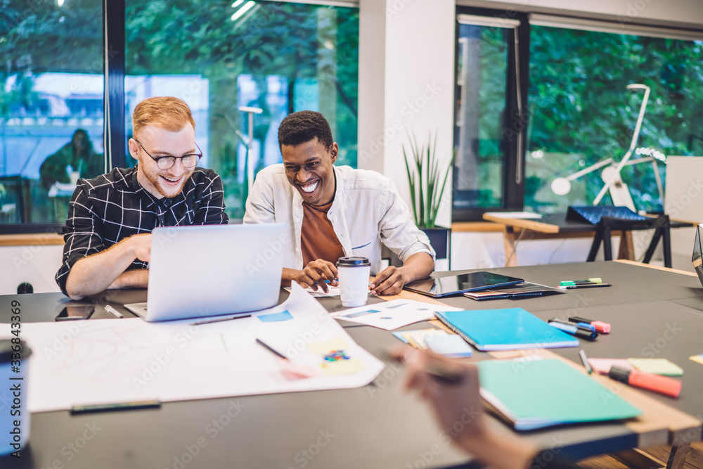 Cheerful multiethnic students working on project in library