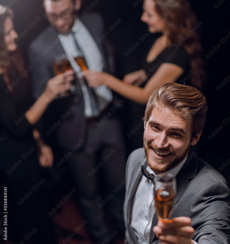 stylish young man standing with a glass of champagne.