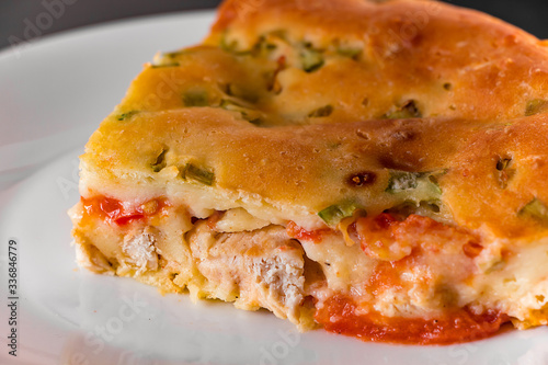 Delicious homemade pie with chicken, herbs and tomatoes on a plate.