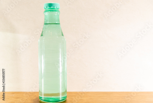 Colored glass bottles with natural water on light and illuminated background