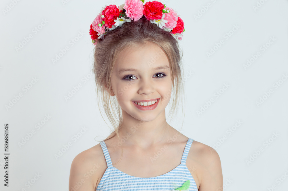 Close up portrait little cheerful Girl Smiling in the Camera in wreath of flowers Close up portrait little cheerful Girl Smiling in the Camera in wreath of flowers