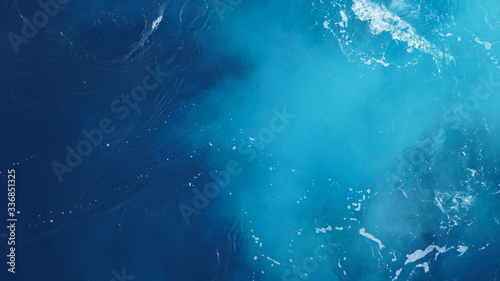 close-up wavy blue ocean surface, foam streaks on sea water