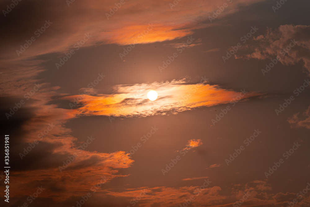 Dramatic late afternoon sky and sun between clouds forming a spiraling geometric figure