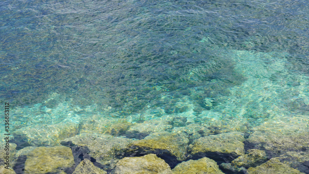 rocky shore. big green stones in turquoise blue water of the ocean. clear  sea water off the coast of a tropical island