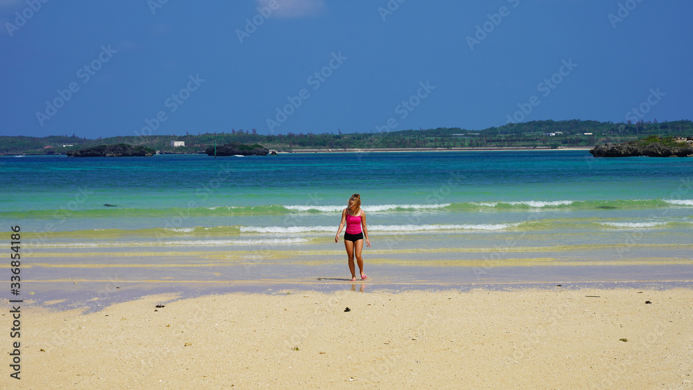 beautiful girl model in pink clothes on the ocean shore. blonde walks on a clean beach by the sea. tropical island vacation