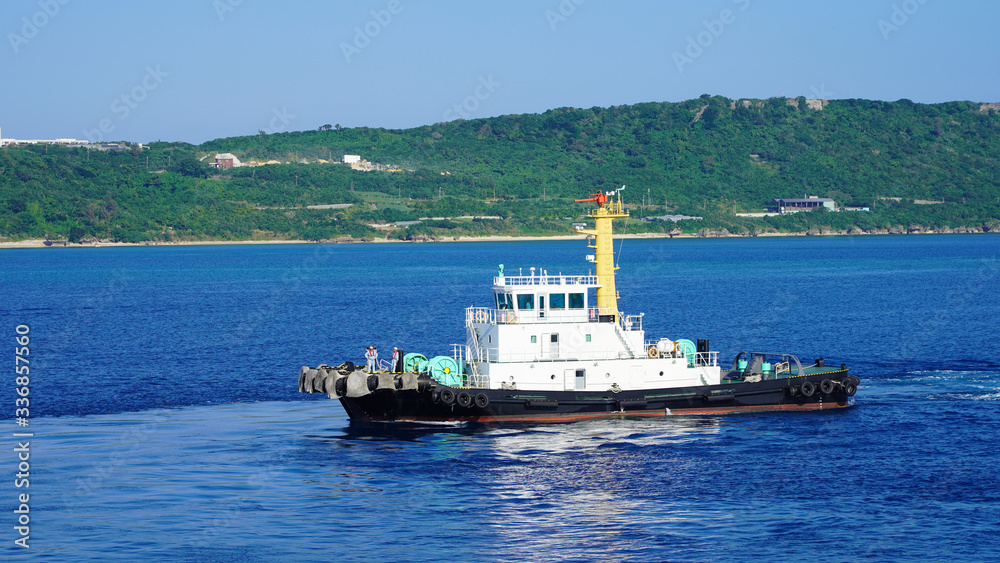Colored tugboat works in port. bright tugboat in blue water. industrial ship on waves tropical islands. powerful tugboat helps maneuvering big ship
turquoise blue Pacific Ocean Okinawa japan