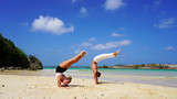 beautiful girl and guy acrobats do handstand on the white sand of the beach. couple in white doing acrobatic elements on the ocean on a sunny day. flexible back. back band pose