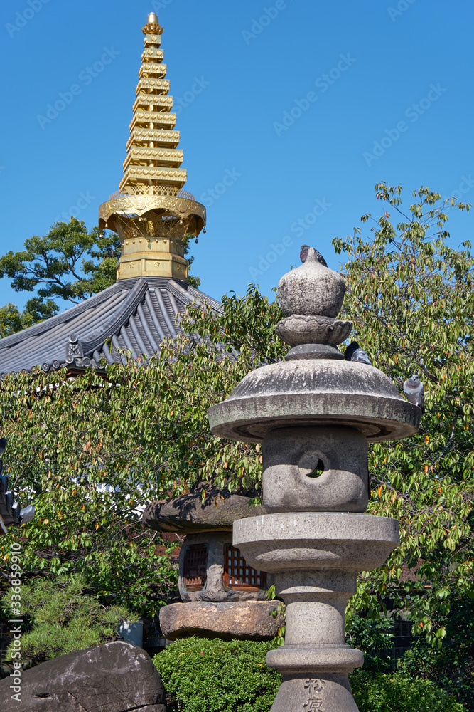 Traditional stone lanterns with pagoda sorin on the background in the temple garden. Osaka. Japan