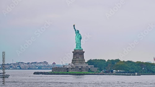 NEW YORK, USA - OCTOBER 2, 2018: Camera on board passes the Statue of Liberty on Liberty Island during the gloomy weather, designed by French Frederic Auguste Bartholdi and built by Gustave Eiffel. photo