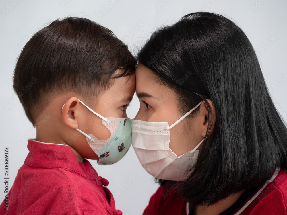 Portrait of asian family mom and son showing love and wearing protective mask trying to protect from virus epidemic over gray background.