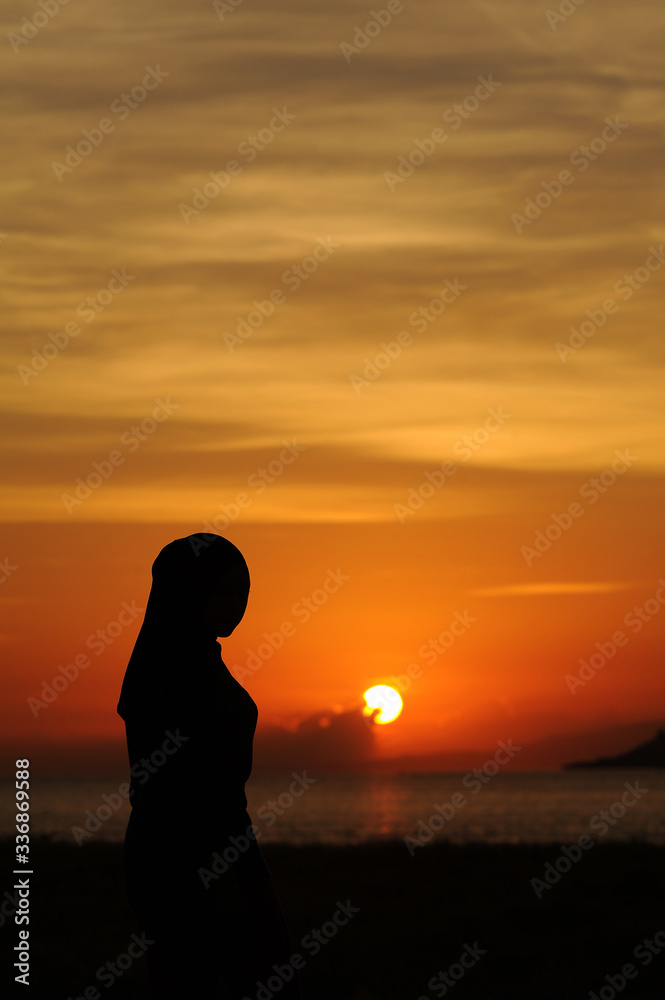 beautiful girl standing on beach at sea at the sunrise