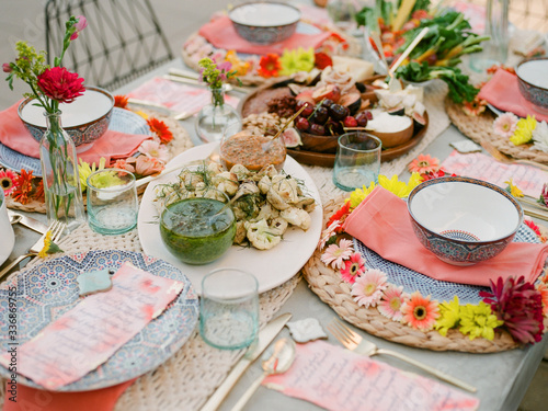 A table scape decorated with colorful plates and summer flowers  awaiting guests to arrive