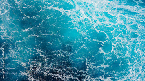 Sea blue water surface background, foam streaks on natural ocean background. Aerial view of the ocean