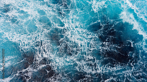 background pacific ocean during a typhoon, bright blue color of a sea splashing wave, texture of sea foam. abstraction of ripped water waves in the ocean in a storm sunlight. turbulent ocean
