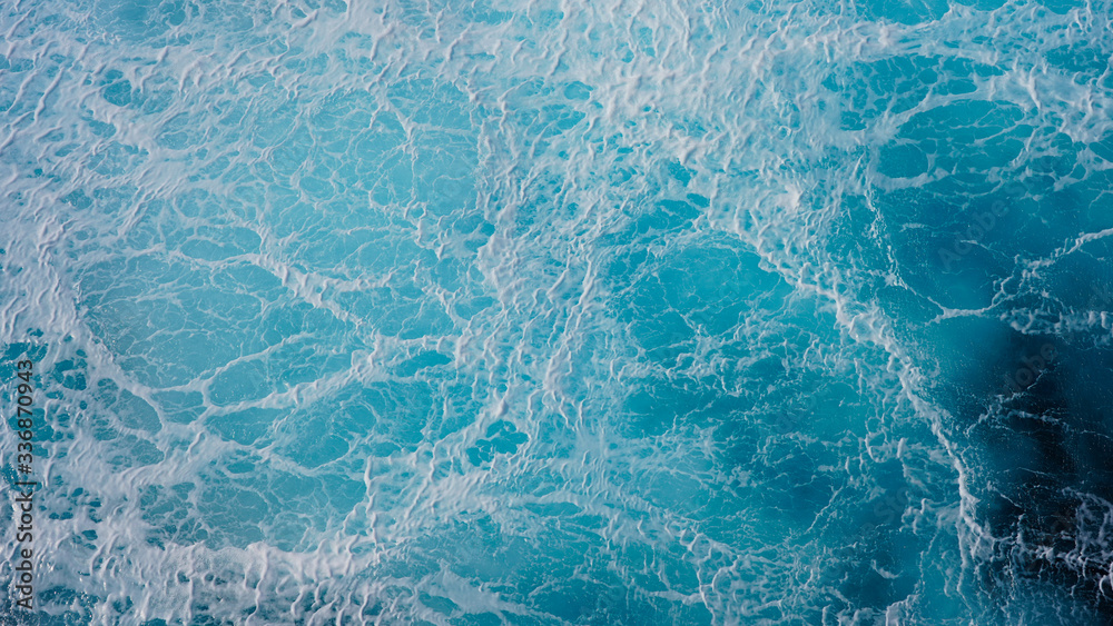 Sea blue water surface background, foam streaks on natural ocean background. Aerial view of the ocean Sea blue water surface background, foam streaks on natural ocean background. Aerial view of the ocean
