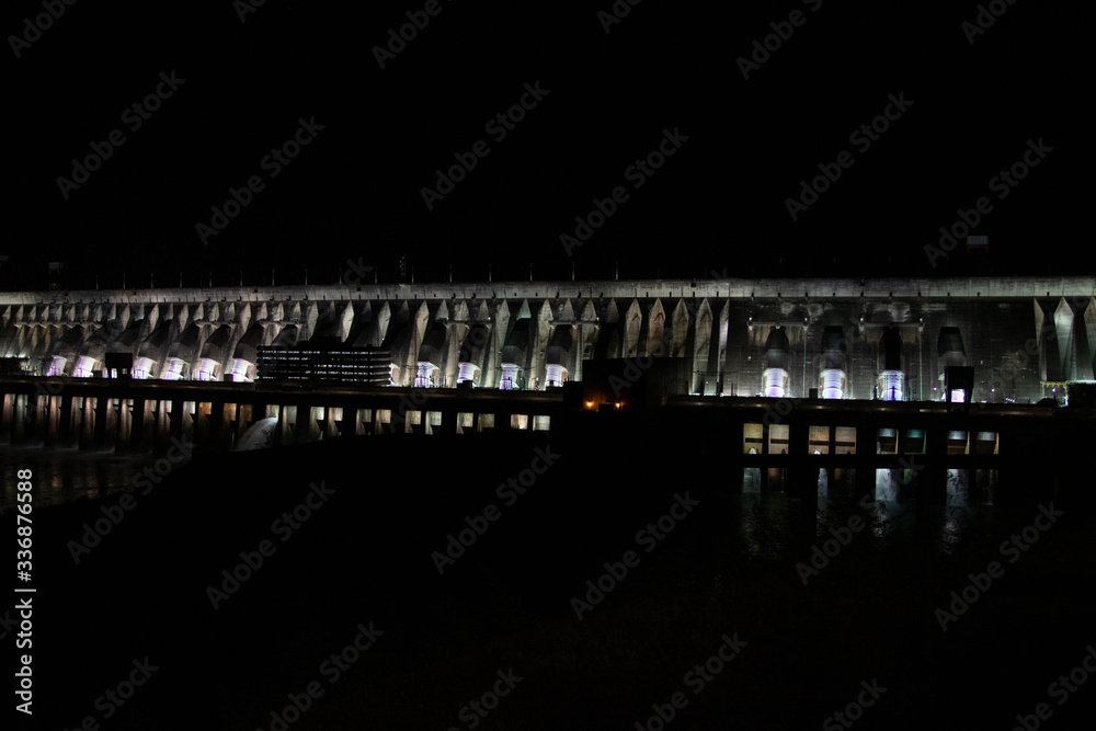 Fototapeta premium View of the illuminated Itaipu Dam at night. The biggest hydroelectric dam, on the Parana River located between Brazil and Paraguay.