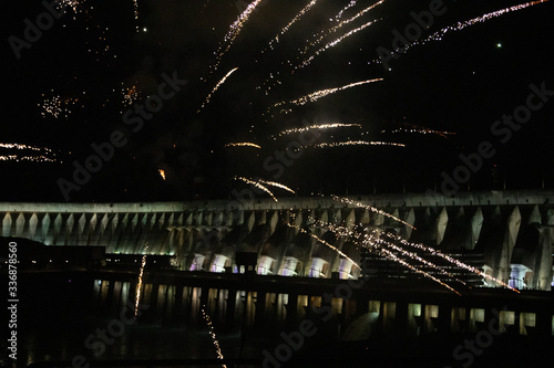 View of the illuminated Itaipu Dam at night with fireworks. The biggest hydroelectric dam  on the Parana River located between Brazil and Paraguay.