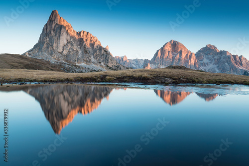 View of famous Dolomites mountain peaks glowing in beautiful golden morning light at sunrise in summer, South Tyrol,Italy Ra Gusella and Giau pass reflection in lake. Famous best alpine place in Alps. © Michal