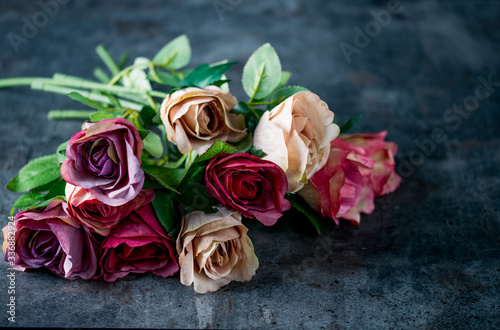 Artificial antique roses on stony background.