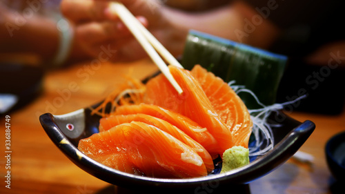 Asian people eating sashimi set in Asian restaurant. Hirame sashimi,salmon sashimi and tuna sashimi dish. Japanese food concept.