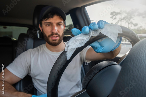 Photography A bearded brown haired man wearing a baseball cap uses alcohol wipes to steriliz