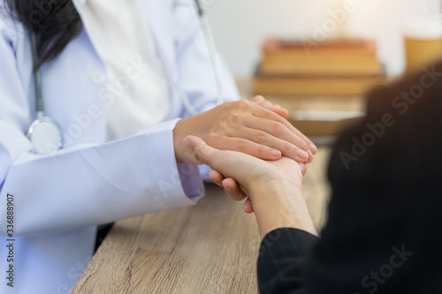 Close up and crop shoot of young Asian female doctor holds an adult female patient’s hand to examine and diagnose her sickness and symptom. Medicine and health care concept. Doctor and patient.