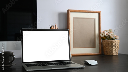 Wallpaper Mural Photo of black working desk along with white blank screen computer laptop, books, notebook, pencil holder, picture frame, potted plant putting together on it with white cement wall as background. Torontodigital.ca