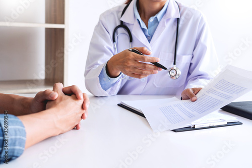 patient listening intently to a male doctor explaining patient symptoms or asking a question as they discuss paperwork together in a consultation