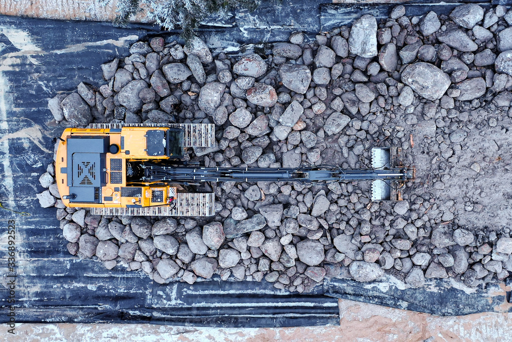 Top down shot of an excavator sitting on top of a rocky bed.