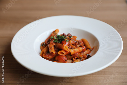 Penne arrabiata pasta tomato sauce with spices italian food on wood background