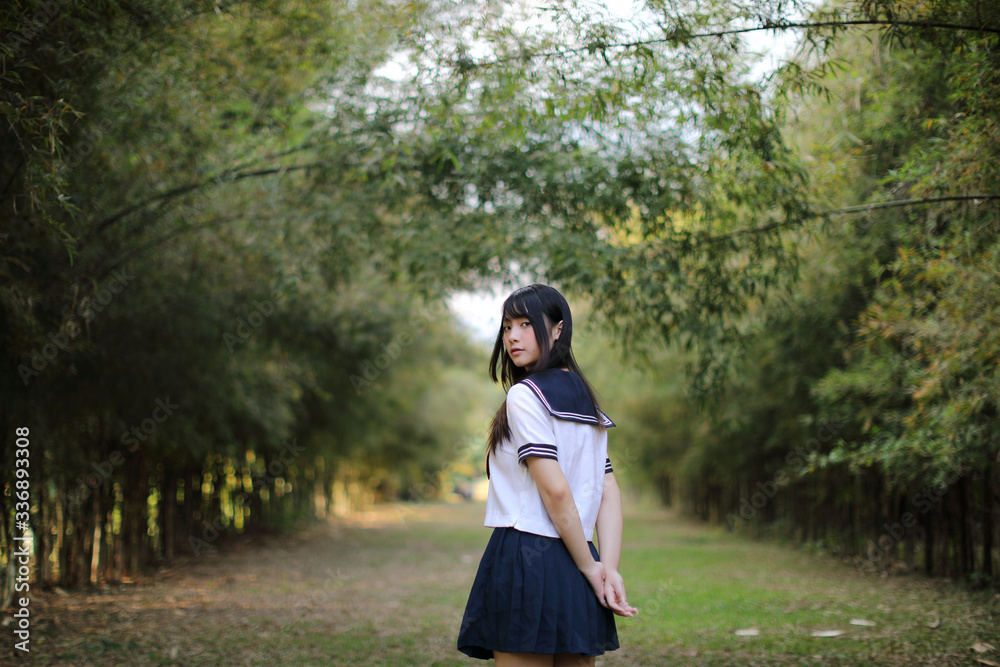 Portrait of beautiful Asian japanese high school girl uniform looking with bamboo forest background Portrait of beautiful Asian japanese high school girl uniform looking with bamboo forest background