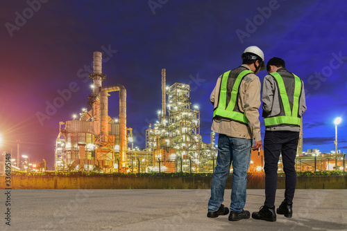 Workers engineer in Oil and gas industrial, Oil refinery plant from industry, Refinery Oil storage tank and pipe line steel on twilight, evening background.